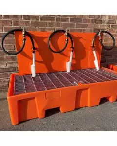 Orange boot wash station with three spray nozzles and a grated floor, designed for cleaning footwear on construction sites.