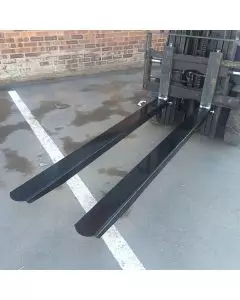 Heavy-duty bolt-on forklift fork extensions fitted to standard forks for handling larger and longer loads in industrial environments